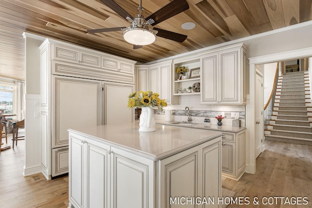 kitchen with sink, a center island, wood ceiling, light hardwood / wood-style floors, and paneled refrigerator