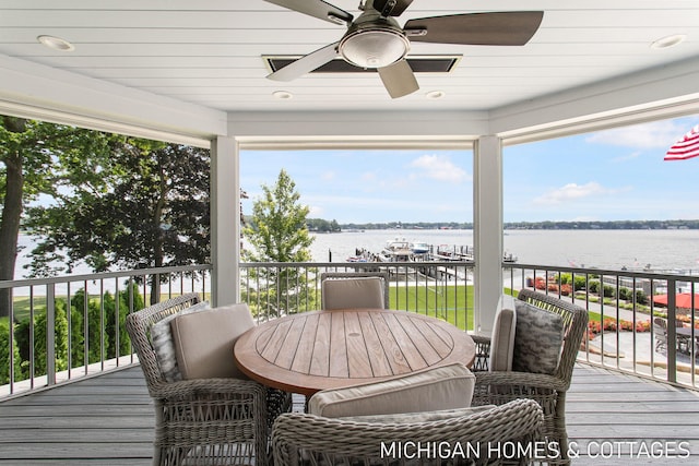 wooden terrace with a water view and ceiling fan