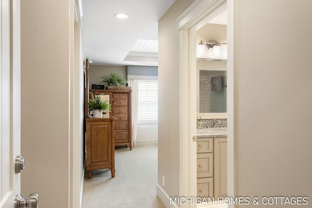 hall with light carpet and a tray ceiling