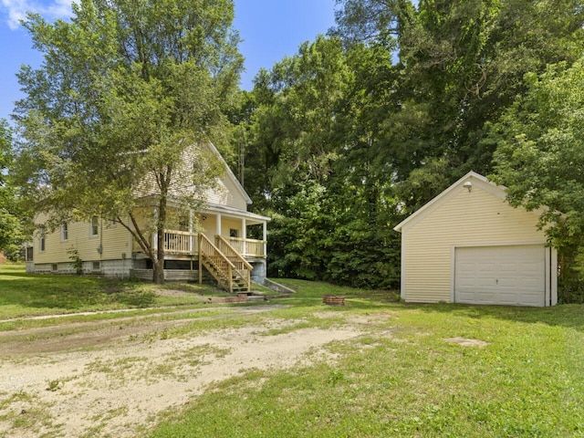 view of yard with a garage, an outbuilding, covered porch, and a fire pit