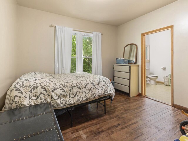 bedroom with dark wood-type flooring and connected bathroom