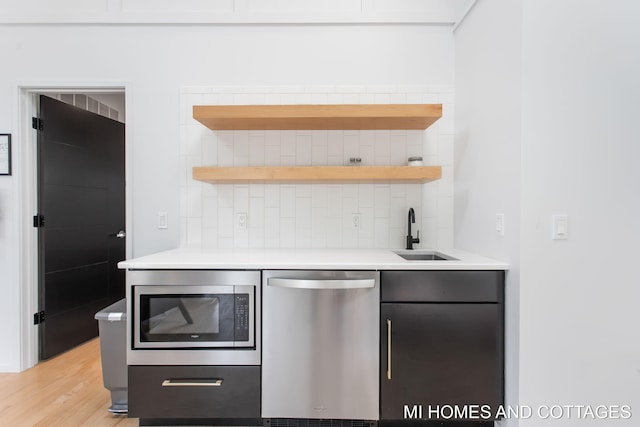 kitchen with sink, light hardwood / wood-style flooring, stainless steel appliances, and backsplash