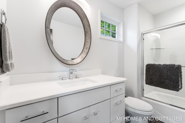 full bathroom featuring toilet, vanity, and enclosed tub / shower combo