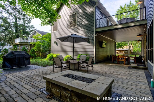 view of patio / terrace with a balcony, an outdoor fire pit, and exterior bar