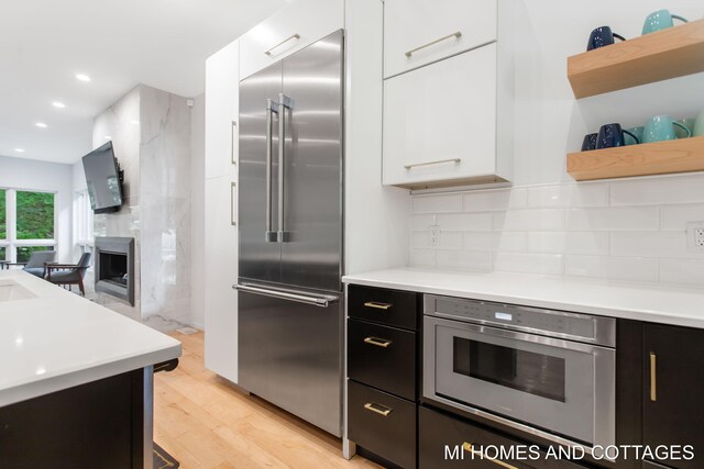 kitchen featuring white cabinetry, light wood-type flooring, stainless steel appliances, and backsplash