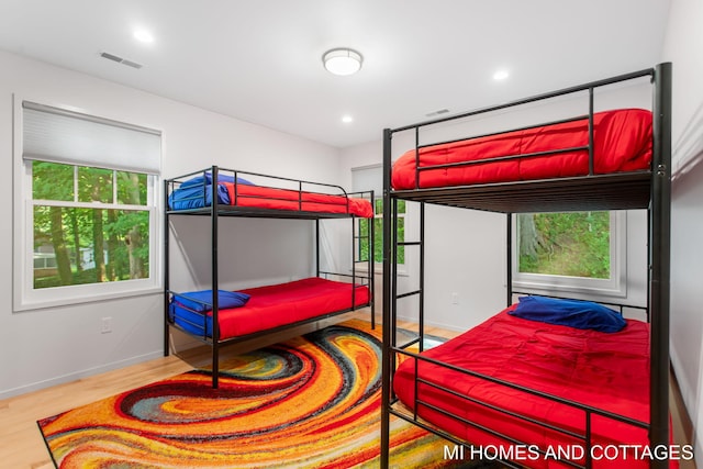 bedroom with multiple windows and light hardwood / wood-style flooring