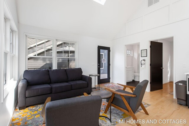 living room featuring high vaulted ceiling and light wood-type flooring