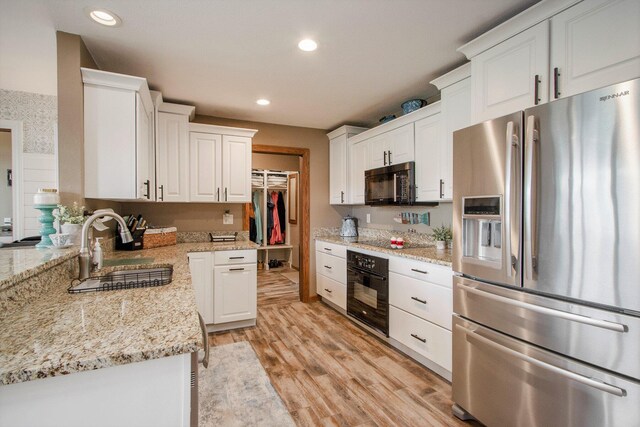 kitchen featuring black appliances, light wood-type flooring, sink, and white cabinetry