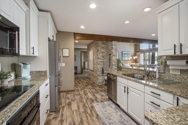 kitchen with light wood-type flooring, stainless steel appliances, and white cabinetry