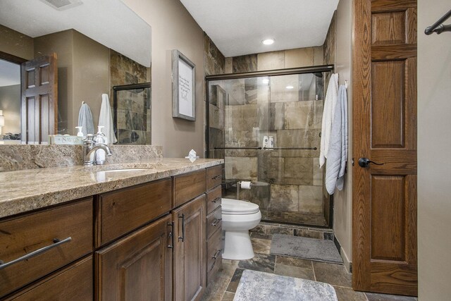 bathroom with toilet, tile patterned floors, vanity, and a shower with shower door