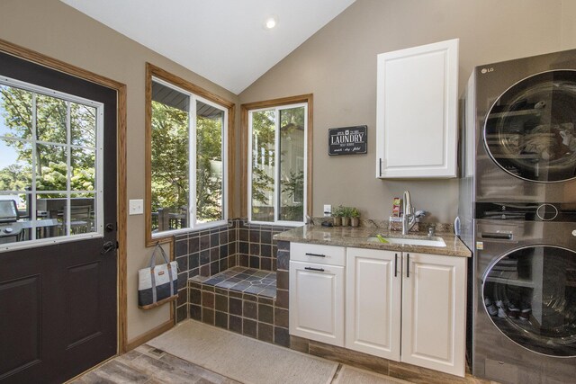 bathroom with plenty of natural light, vaulted ceiling, and stacked washer and clothes dryer