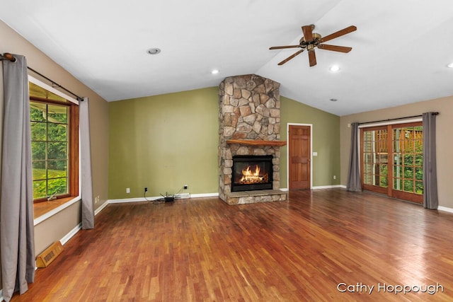 unfurnished living room with lofted ceiling, hardwood / wood-style floors, a stone fireplace, and ceiling fan