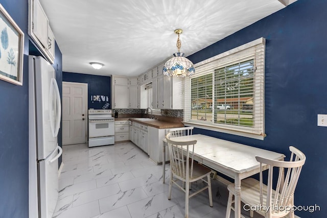 kitchen featuring hanging light fixtures, white cabinetry, tasteful backsplash, and white appliances