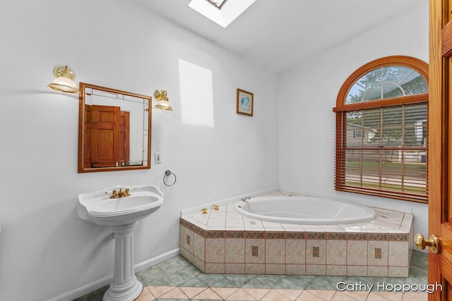 bathroom featuring a relaxing tiled tub, tile patterned flooring, and vaulted ceiling with skylight