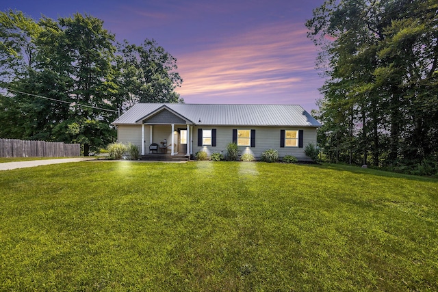 single story home featuring covered porch and a lawn