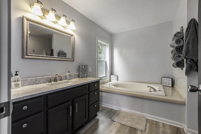 bathroom with vanity, a tub to relax in, and wood-type flooring