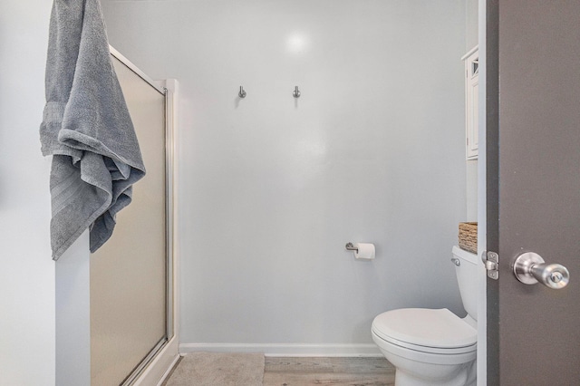 bathroom with wood-type flooring, an enclosed shower, and toilet