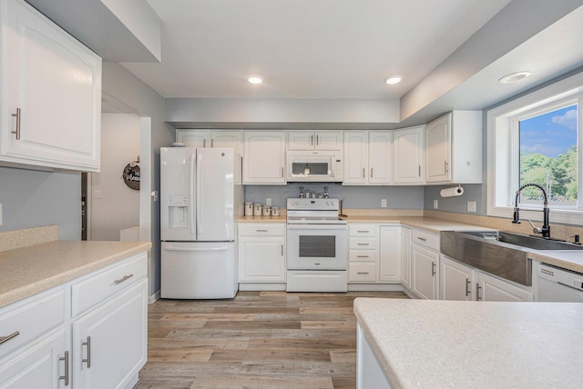 kitchen featuring white appliances, light hardwood / wood-style floors, sink, and white cabinets