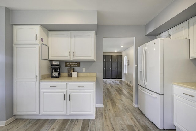 kitchen featuring white cabinetry, light hardwood / wood-style floors, and white fridge with ice dispenser