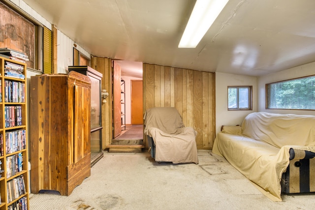 sitting room featuring wooden walls, light colored carpet, and vaulted ceiling