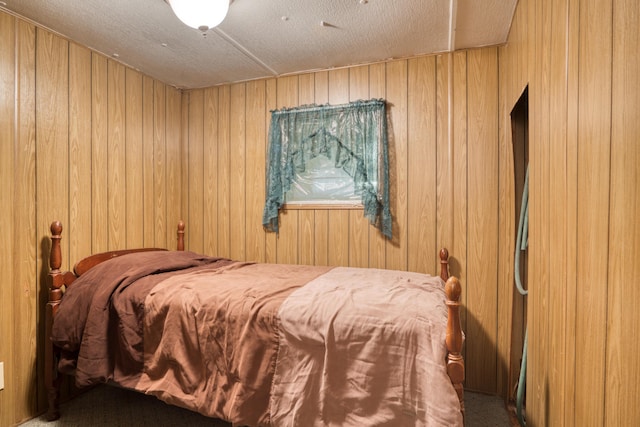 bedroom with a textured ceiling and wood walls