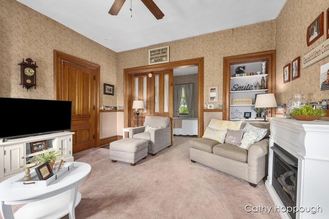 living room featuring light carpet, a fireplace, and ceiling fan