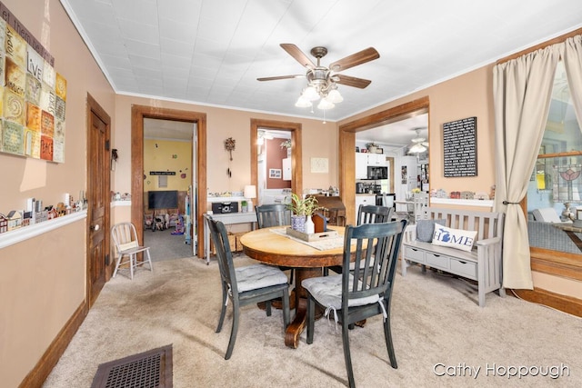 dining room with crown molding, light colored carpet, and ceiling fan