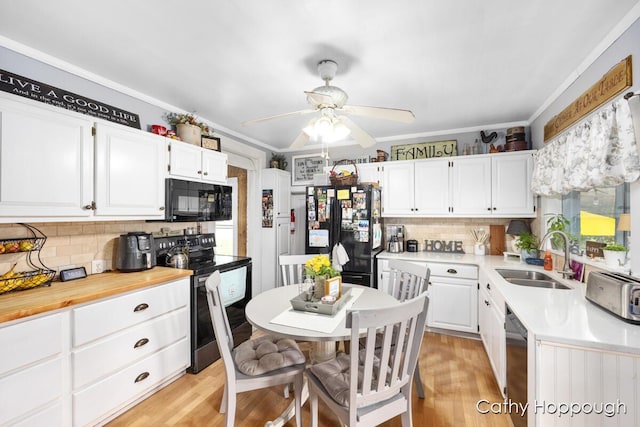 kitchen featuring white cabinetry, ornamental molding, sink, and black appliances