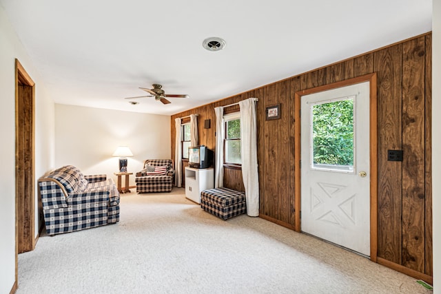 unfurnished room with ceiling fan, light carpet, and wood walls