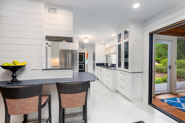 18760 Valencia St, Northville, MI 48168 - kitchen with a peninsula, marble finish floor, stainless steel appliances, dark countertops, and glass insert cabinets