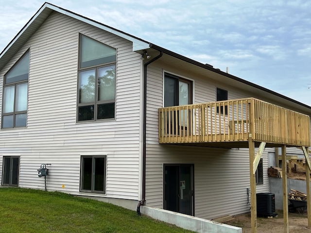 back of house with central AC unit and a lawn