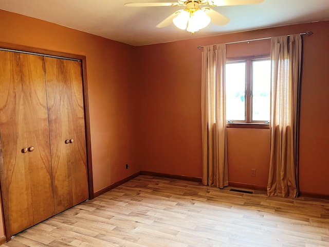 unfurnished bedroom with ceiling fan, a closet, and light wood-type flooring