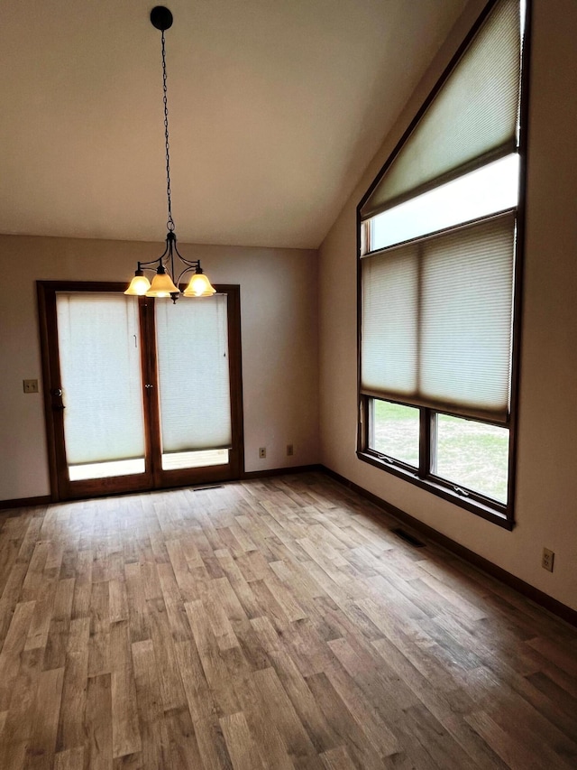 unfurnished dining area with lofted ceiling and hardwood / wood-style floors