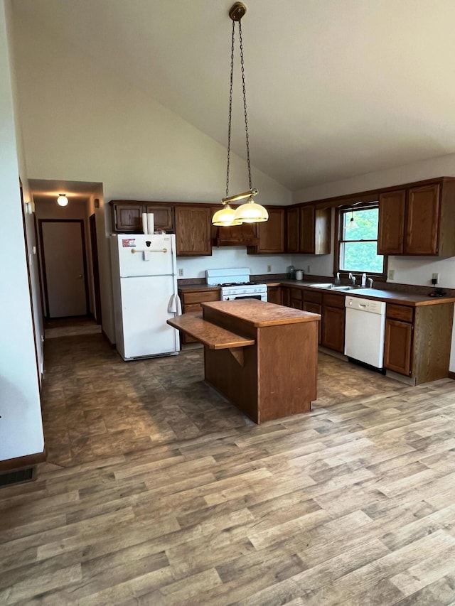 kitchen with high vaulted ceiling, hanging light fixtures, a kitchen island, hardwood / wood-style flooring, and white appliances