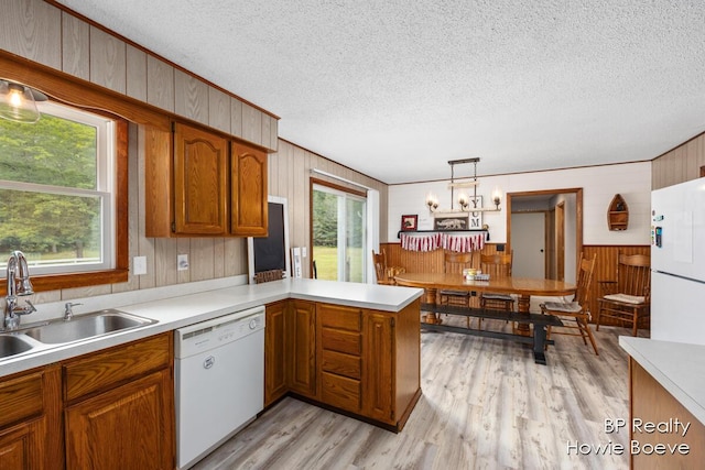 kitchen with sink, hanging light fixtures, white appliances, kitchen peninsula, and a textured ceiling