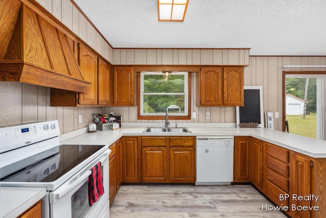 kitchen with sink, custom exhaust hood, kitchen peninsula, white appliances, and light hardwood / wood-style flooring