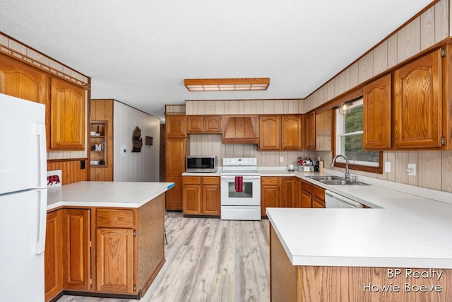 kitchen with sink, a textured ceiling, light hardwood / wood-style flooring, kitchen peninsula, and white appliances