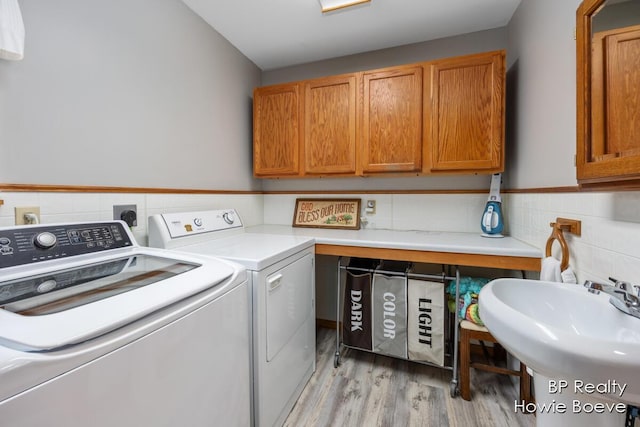 laundry room with cabinets, sink, washing machine and clothes dryer, and light wood-type flooring