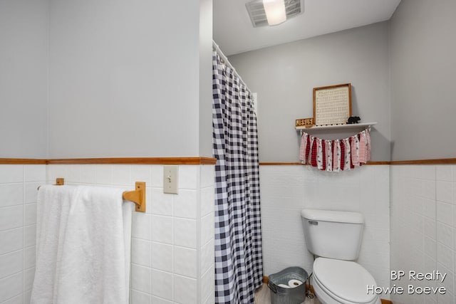 bathroom featuring tile walls and toilet