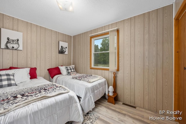 bedroom with wooden walls and light hardwood / wood-style flooring