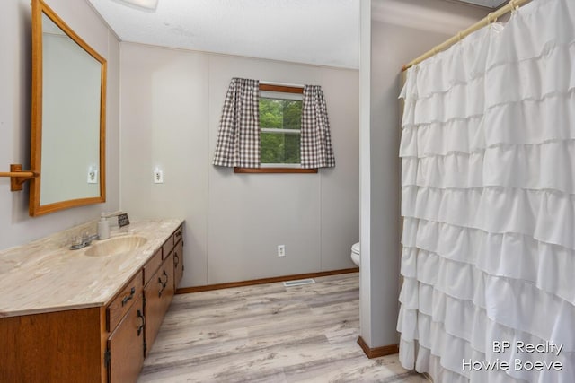 bathroom featuring walk in shower, toilet, a textured ceiling, vanity, and hardwood / wood-style flooring