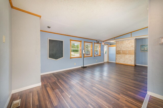 unfurnished living room with vaulted ceiling, crown molding, dark hardwood / wood-style floors, a textured ceiling, and brick wall