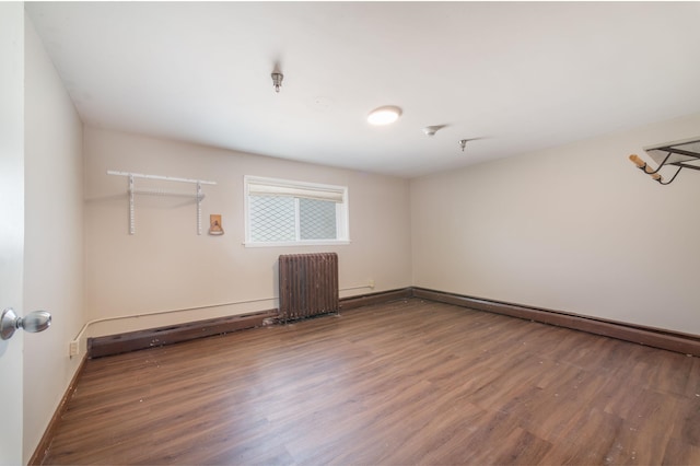 spare room with radiator heating unit, a baseboard heating unit, and hardwood / wood-style floors