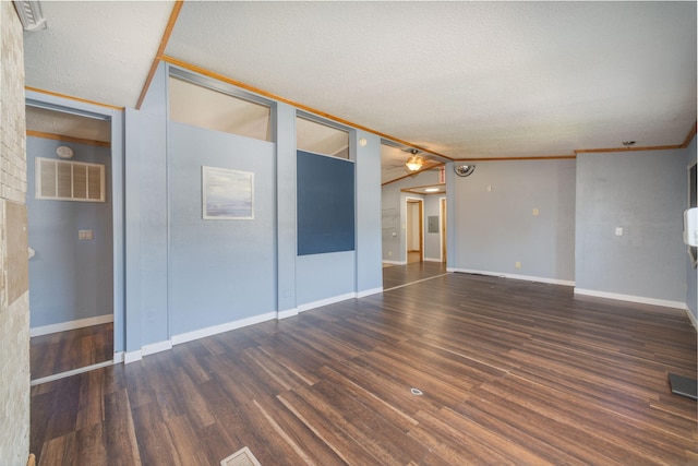 empty room with lofted ceiling, wood-type flooring, crown molding, and a textured ceiling