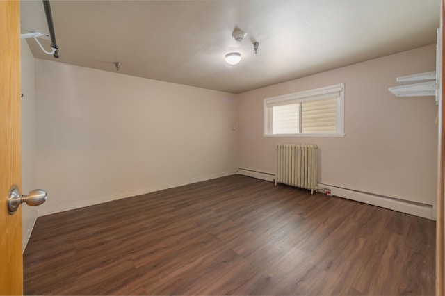 empty room featuring radiator, a baseboard heating unit, and dark wood-type flooring