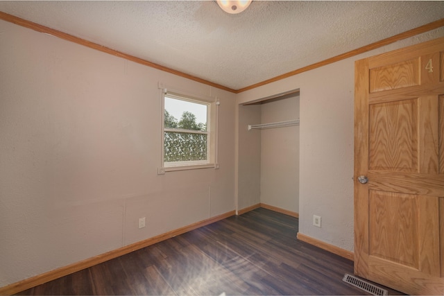 unfurnished bedroom featuring crown molding, a textured ceiling, dark hardwood / wood-style flooring, and a closet