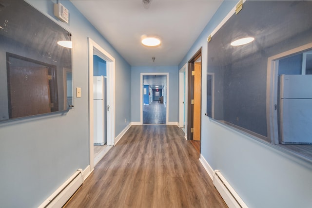 corridor with hardwood / wood-style flooring and baseboard heating