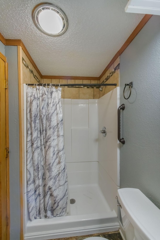 bathroom with walk in shower, toilet, and a textured ceiling