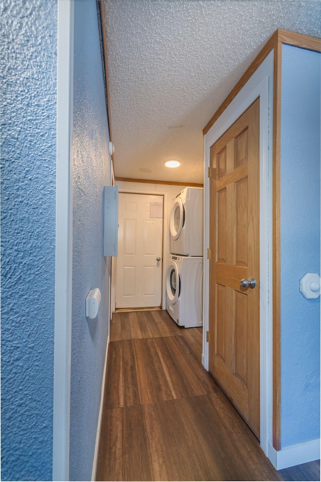 laundry room featuring stacked washer / dryer, a textured ceiling, and dark hardwood / wood-style floors