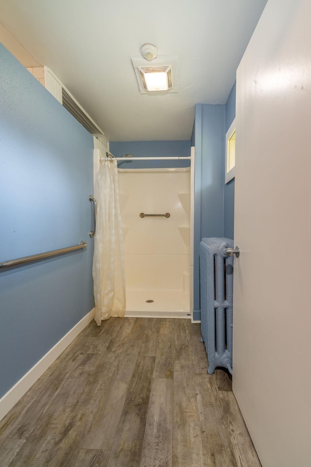 bathroom featuring hardwood / wood-style flooring, radiator, and curtained shower